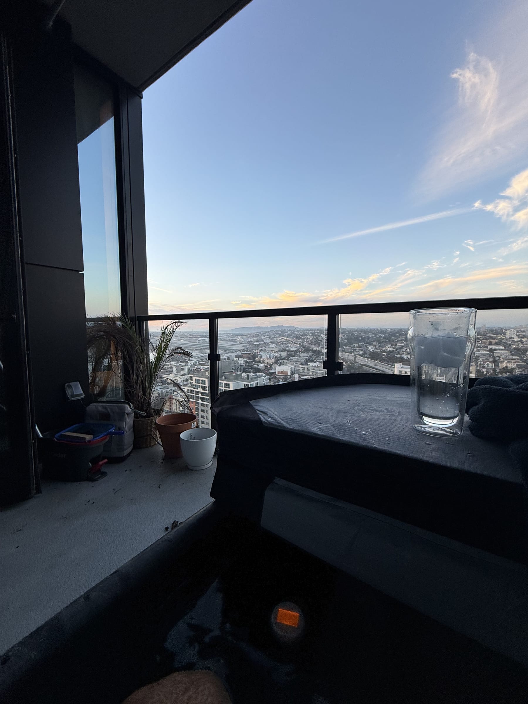 View from inside an Arctic Forge cold plunge on a 32nd-floor balcony — city skyline at dusk